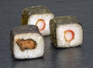 Various sushi dishes on dark grey stone surface