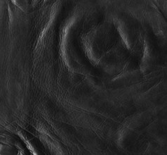 Full frame abstract background showing a old black rippled leather surface