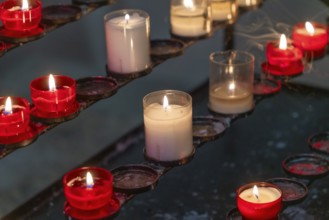 Closeup shot of some votive candles on a votive candle rack in dark ambiance