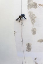 DEU Germany Germany Berlin A worker painting a façade while hanging from a rope