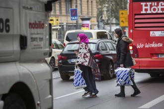 DEU Germany Germany Berlin Two woman try to cross the main street in Schöneberg with shopping bags