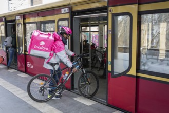 DEU Germany Germany Berlin A Foodora food courier boards an S-Bahn train with his equipment