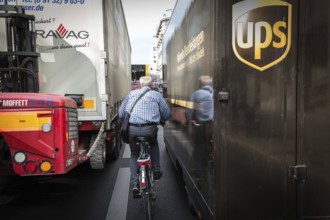 DEU Germany Germany Berlin A cyclist rides between two lorries on Rudi-Durschke-Str