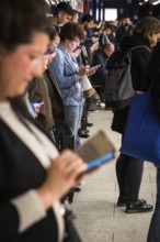 DEU Germany Germany Berlin Passengers look at their mobile phones while waiting for the train at