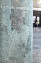 DEU Germany Germany Berlin Woman talking on the phone at a phone box with shattered glass in