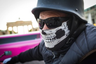 DEU Germany Germany Berlin A motorcyclist with a mask and sunglasses in front of the Brandenburg