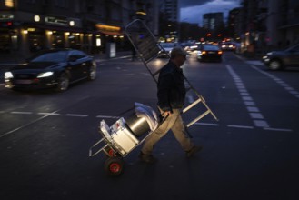 DEU Germany Germany Berlin A craftsman passes Nürnberger Straße in the evening with his tools