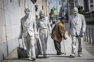 DEU Germany Germany Berlin Three people painted in grey walk along the wall of the Ministry of