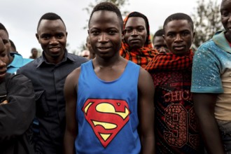 TZA TANZANIA Benaco Young people listen to a nappy salesman in a marketplace. A man in a superman