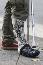 DEU Germany Germany Berlin A man with a painting on his plaster leg waits at a traffic light on