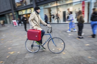 DEU Germany Germany Berlin A cyclist rides with a suitcase on the pavement