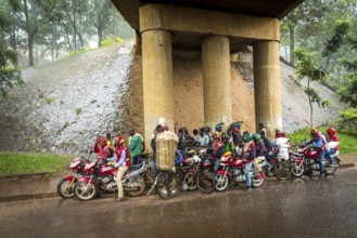 RWA RWANDA RUANDA Kigali Taxi drivers with motorbikes and bicycles wait under a bridge for the end