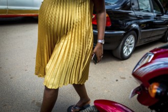 RWA RWANDA RUANDA Kigali A pregnant woman in a golden dress walks through the streets of Remera