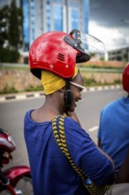 RWA RWANDA RUANDA Kigali A woman with a high hairstyle locks her helmet in front of taking a taxi