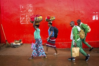 RWA RWANDA RUANDA Kigali People in colourful clothes walk along a red wall