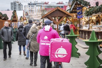 DEU Germany Germany Berlin A Foodora food courier rides his bike through the Christmas market on