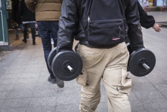 DEU Germany Germany Berlin A man carries two dumbbells in his hands on his way to the underground