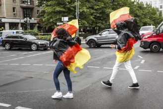 DEU Germany Germany Berlin Two tourists with rain capes in the colours of Germany while sight