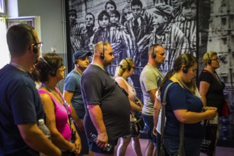 POL Poland Poland Auschwitz visitors in a barrack in front of a photograph of children at the