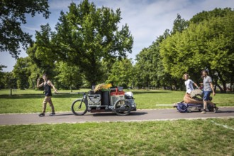 DEU Germany Germany Berlin Young men transporting technology for an event through Volkspark