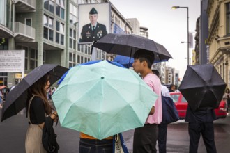 DEU Germany Germany Berlin Tourists with umbrellas at Checkpoint Charlie