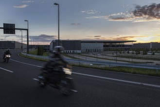 DEU Germany Germany Berlin Motorbikes pass the future BER Berlin-Brandenburg airport at sunset