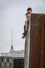 DEU Germany Germany Berlin In summer temperatures, two young people sit on a wall on the Spreebogen