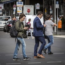 DEU Germany Germany Berlin A young man walks along Friedrichsstrasse reading while another looks at