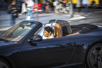 DEU Germany Germany Berlin A woman is dazzled by the sun as she drives her convertible across