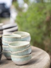 Stacked handmade ceramic bowls displaying rustic green glaze and earthy textures on a wooden