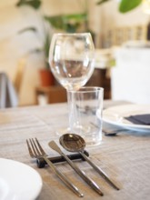 Elegant restaurant table arranging cutlery, plates, and glasses on a linen tablecloth