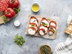 Caprese bruschetta with fresh ingredients on a light gray background, ready to eat
