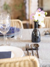 Decorated restaurant table with a flower vase, clean plates, glasses, and modern cutlery