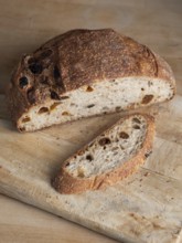 Freshly baked sourdough bread with raisins on a rustic cutting board