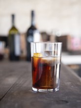 Refreshing vermouth cocktail with ice and orange on a wooden table