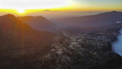 Fog lying between the mountains at sunrise, photograped with a drone