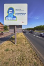 Welcome to Gutenberg City, tourist sign, roads, lanes, central island, lantern, trees, lawn, blue