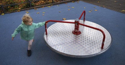 Outdoor shot, little girl, child, 4 years, blonde, playing with carousel, movement effect,
