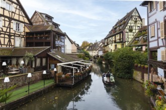 Traditional houses along a river, here called the little Venice, with tourists visiting Colmar on a