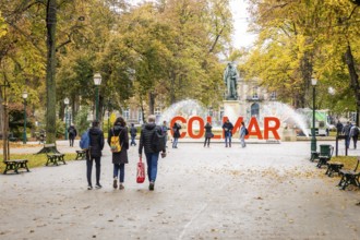 Tourists walking around the red lettering in the square Rapp of the city of Colmar, Alsace, France