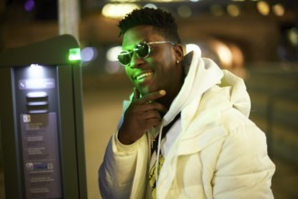 Thoughtful greenlit African man at parking ticket machine pausing as symbol for approved