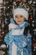 Young girl dressed as snegurochka smiling in front of a decorated christmas tree.Belarus