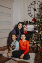 Family group portrait showing a mother, children, and kitten in a festive christmas home setting