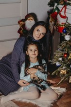 Mother and daughter happily posing with a tabby kitten during christmas holidays.Belarus
