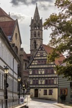 Picturesque alley with half-timbered house and church under cloudy sky, historic atmosphere, the