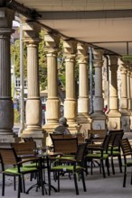 Historic outdoor café under pillars with green chairs and a quiet atmosphere in the city, arcades