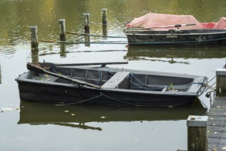 Borken-Hoxfeld, NRW, Germany, A weathered black boat is moored at the dock, surrounded by tranquil