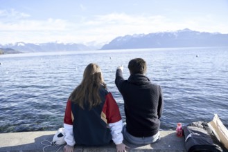 NO MODEL RELEASE, unrecogniseable couple pointing at mountains Les Cornettes de Bise behind Lake
