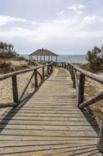 A wooden walkway leads to a cabin by the sea. View of the Atlantic Ocean from the beach of the