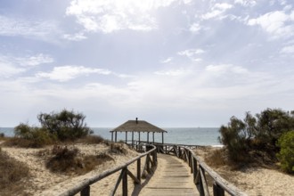 A wooden walkway leads to a cabin by the sea. View of the Atlantic Ocean from the beach of the